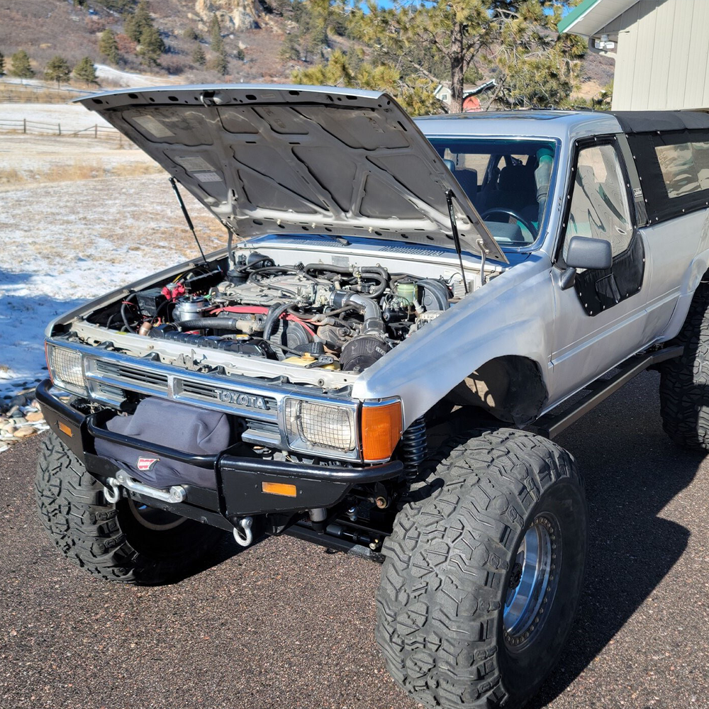 Blue first-generation Toyota 4Runner with hood held open by dual gas struts