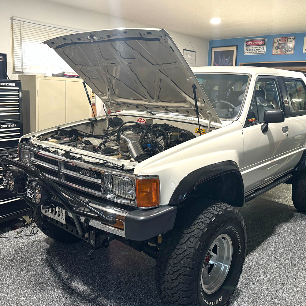 White first-generation Toyota 4Runner with bolt-on hood strut kit installed