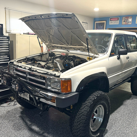 White first-generation Toyota 4Runner with bolt-on hood strut kit installed