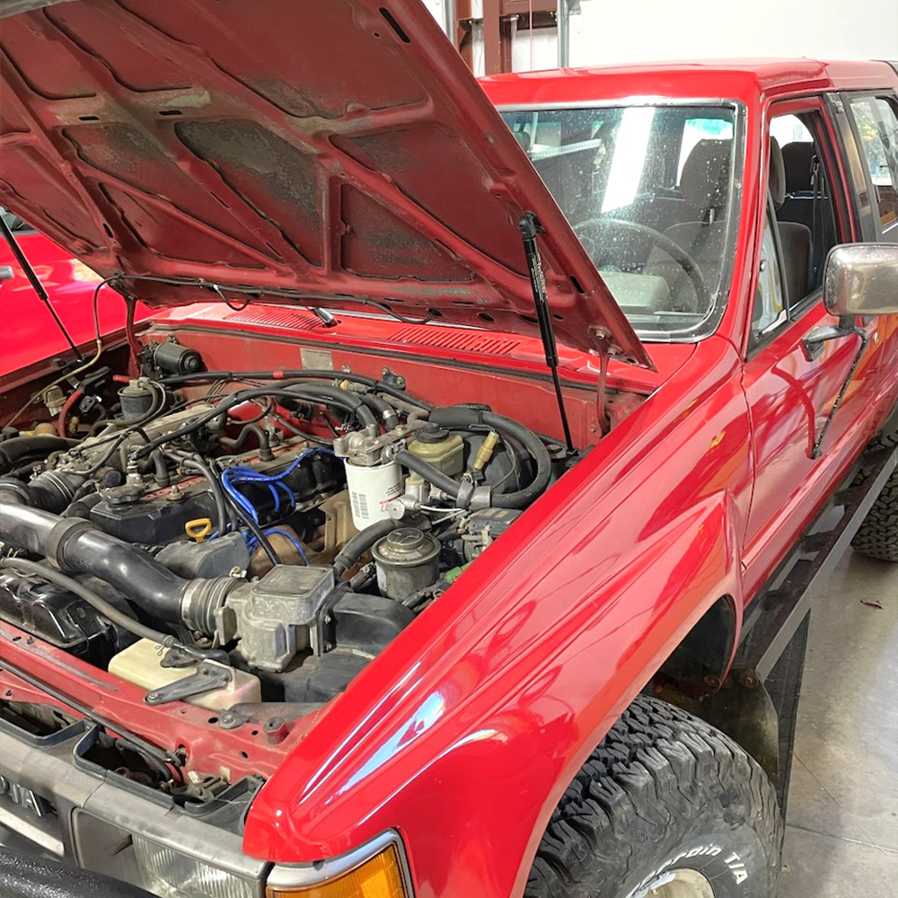 Red 1984-88 Toyota Pickup with bolt-on hood strut kit installed