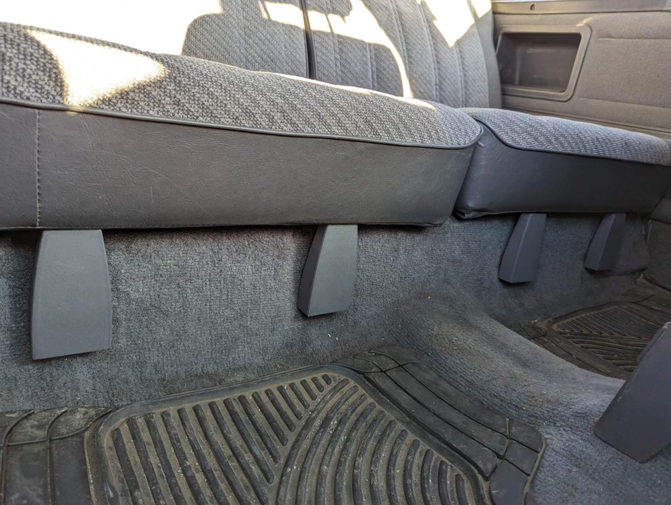 Gray rear seat hinge covers installed beneath the rear seat of a 1984-89 Toyota 4Runner